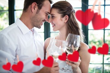 Couple toasting wine glasses at home with hanging hearts around