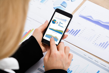 Businesswoman Analyzing Graph Using Mobilephone