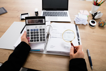 Businesswoman Calculating Invoice Using Calculator