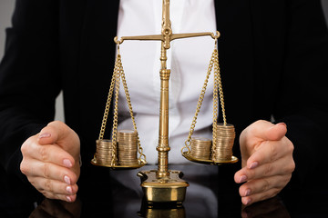Lawyer's Hand Protecting Justice Scale With Coins