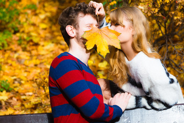 Fototapeta premium couple with maple leaf kissing in autumn park