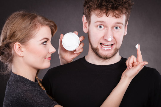 Woman applying cream to her man face.