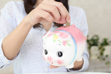 豚の貯金箱を持つ女性