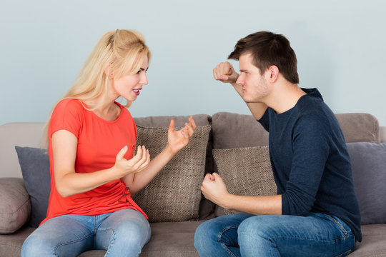 Couple Sitting On Couch Quarreling With Each Other