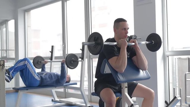 Two men lifting weights at the gym. 