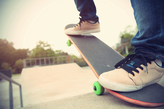 skateboarder legs riding skateboard at skatepark ramp