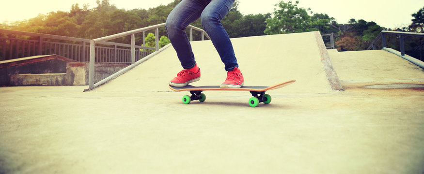 skateboarder legs doing a ollie trick at skatepark