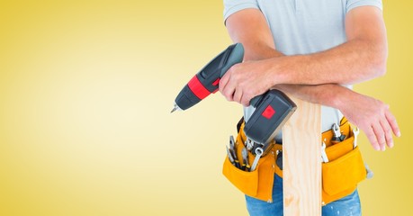 Mid section of handyman holding drill machine and plank