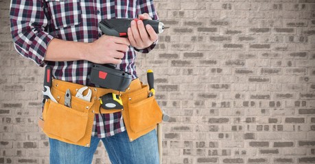 Mid section of handyman with tool belt and drill machine