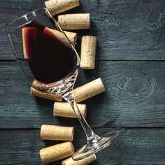 Glass of red wine and corks on dark background