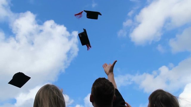 Happy future of graduates, three students throwing academic caps up in the air