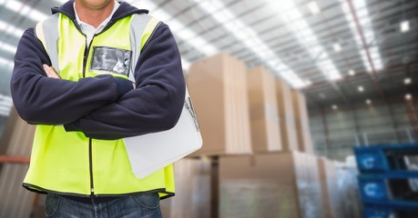 Worker standing with arms crossed in warehouse