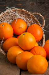 Fresh whole oranges in a basket on a wooden background