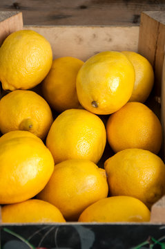 Fresh whole lemons in a box on a wooden background