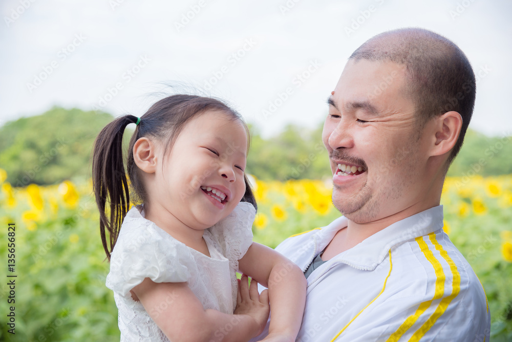 Wall mural Asian father and his daughter smiling in park