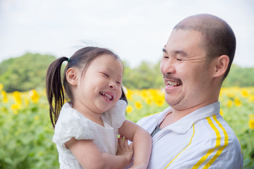 Asian father and his daughter smiling in park