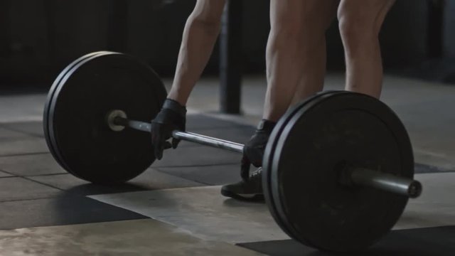 Handheld tracking of strong sportsman lifting barbell and performing front squats 