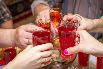 People drink at the table, clink glasses. Cheers