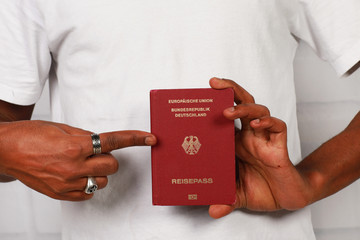schwarze Hand zeigt auf deutschen Pass