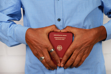 Schwarze Hände halten einen deutschen Pass