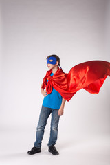 Superhero child in red cape fluttering on wind