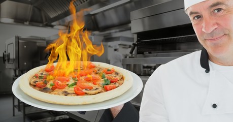 Portrait of chef holding pizza with burning fire