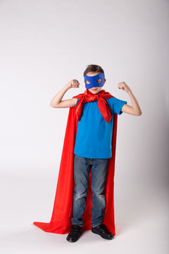 Playful superman kid posing and shows his muscle