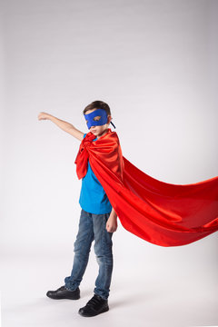 Super hero kid in red cape fluttering on wind