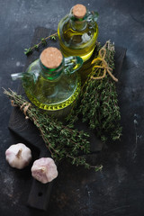 Bottles with olive oil, fresh thyme bunches and garlic
