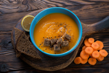 Bowl of carrot cream-soup on a rustic wooden background