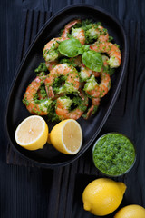 Tiger shrimps with parsley sauce over black wooden background