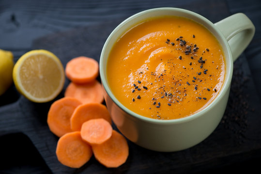 Carrot cream-soup in an olive-colored cup, close-up, studio shot
