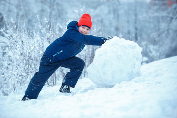 Fototapeta na wymiar Little boy making a snowman
