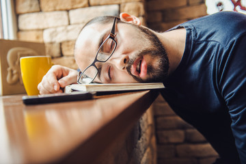 unshaven man in glasses tired, fell asleep at the table