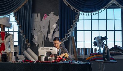 Tailor - girl in the studio, sewing on the sewing machine