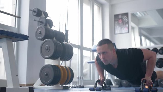 Young man in the gym.Man exercise at the gym.Bodybuilder is training biceps in the gym. A man doing push-ups in the gym