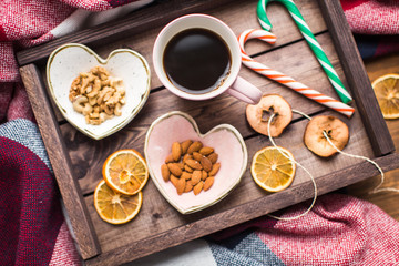 wooden tray with cup of coffee, nuts and orange