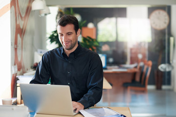 Fototapeta na wymiar Smiling businessman working on a laptop at an office desk