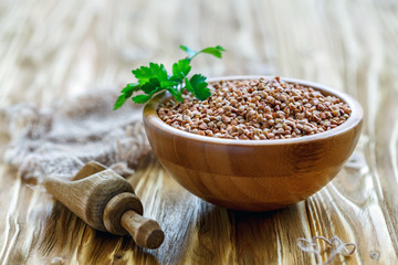 Raw buckwheat in a wooden bowl and scoop.