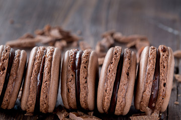 Chocolate macarons on a rustic wooden table. 