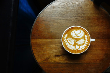 cup of latte art coffee on wooden background