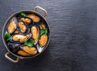 Mussels in copper pan on the graphite background.