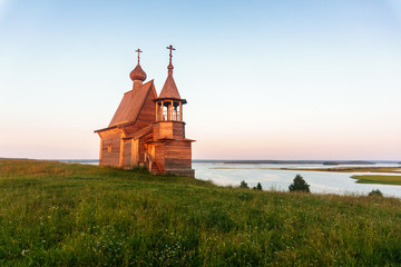 Wooden church on the top of the hill. Vershinino village sunset view. Arkhangelsk region, Northern Russia.