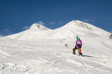 Snowboarder stands and walks on mountain slopes of an extinct volcano Elbrus