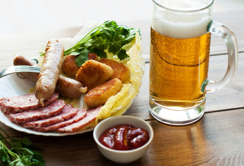Grilled sausages with beer and meat with vegetables and sauce on the table. On the wooden background, banner for cafe