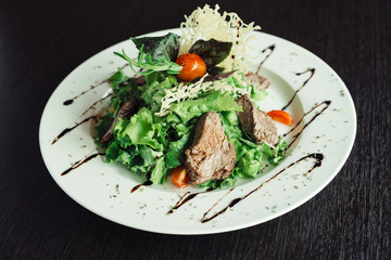 Salad with beef and greens on a white plate