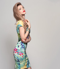 Fototapeta premium Fashion woman in Trendy Spring Summer Dress. Stylish wavy hairstyle, fashion Makeup, Summer Floral Outfit. Glamour Blond lady in Sexy Bodycon, fashion pose. Playful Girl, Luxury summer Accessories