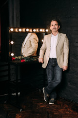Handsome middle aged man is dressed in a casual clothing. Red brick wall background.