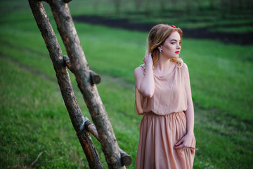 Yong elegance blonde girl at rose dress on the garden background