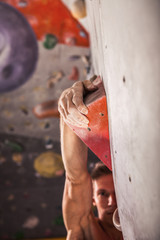 Muscular man practicing rock-climbing